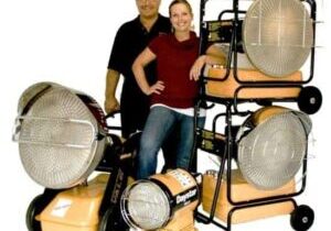 A man and woman posing for the camera with some large heating lamps.